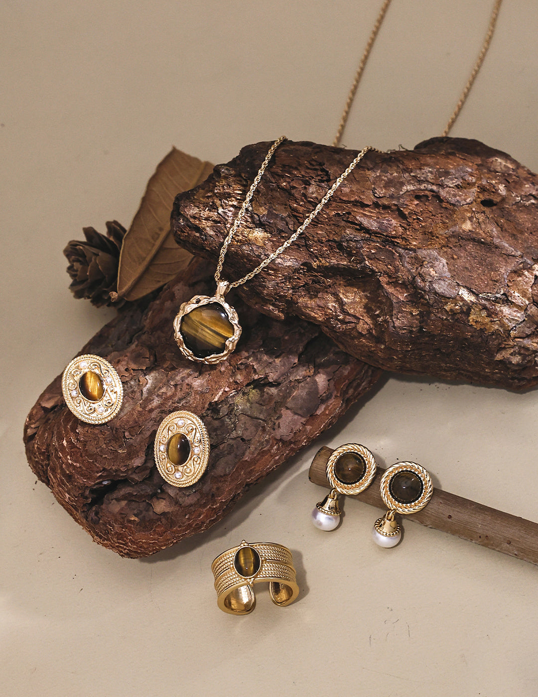 A stunning collection of jewelry featuring a gold plated necklace with a captivating tiger's eye pendant, complemented by matching earrings and a ring.