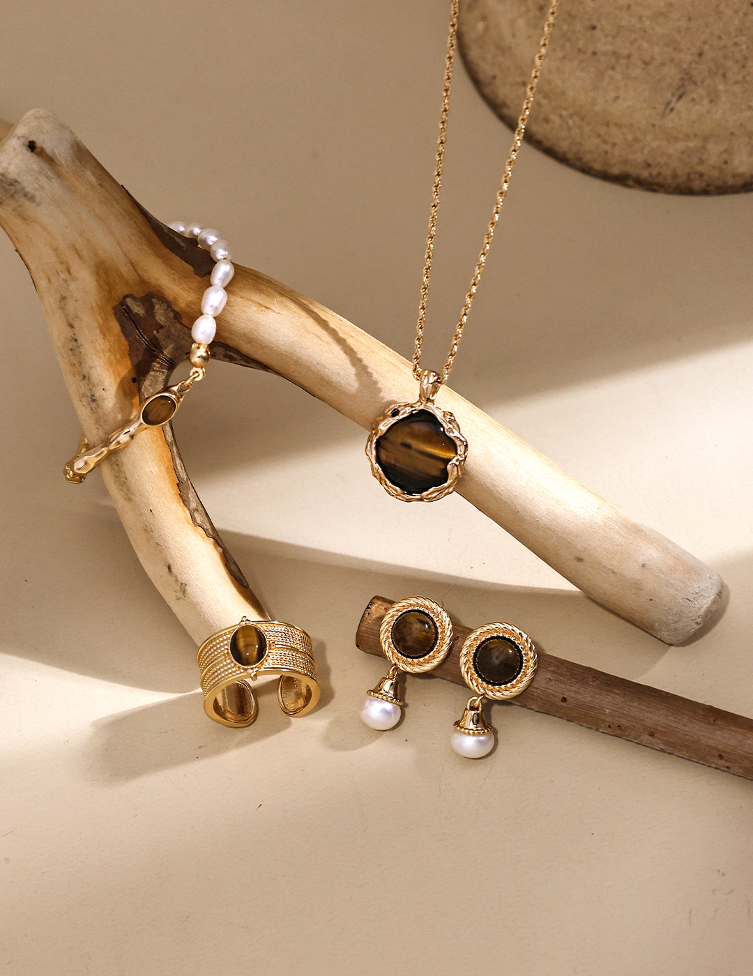 Elegant tiger's eye pendant necklace set with matching earrings and wooden stick.