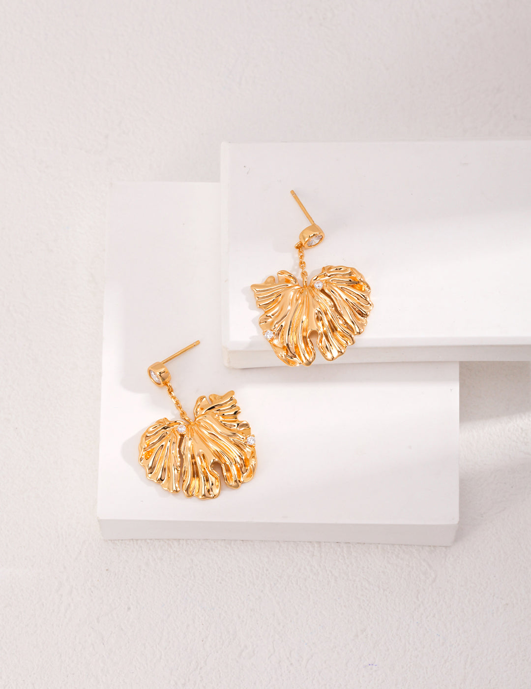  Dainty gold leaf dangle earrings on white background