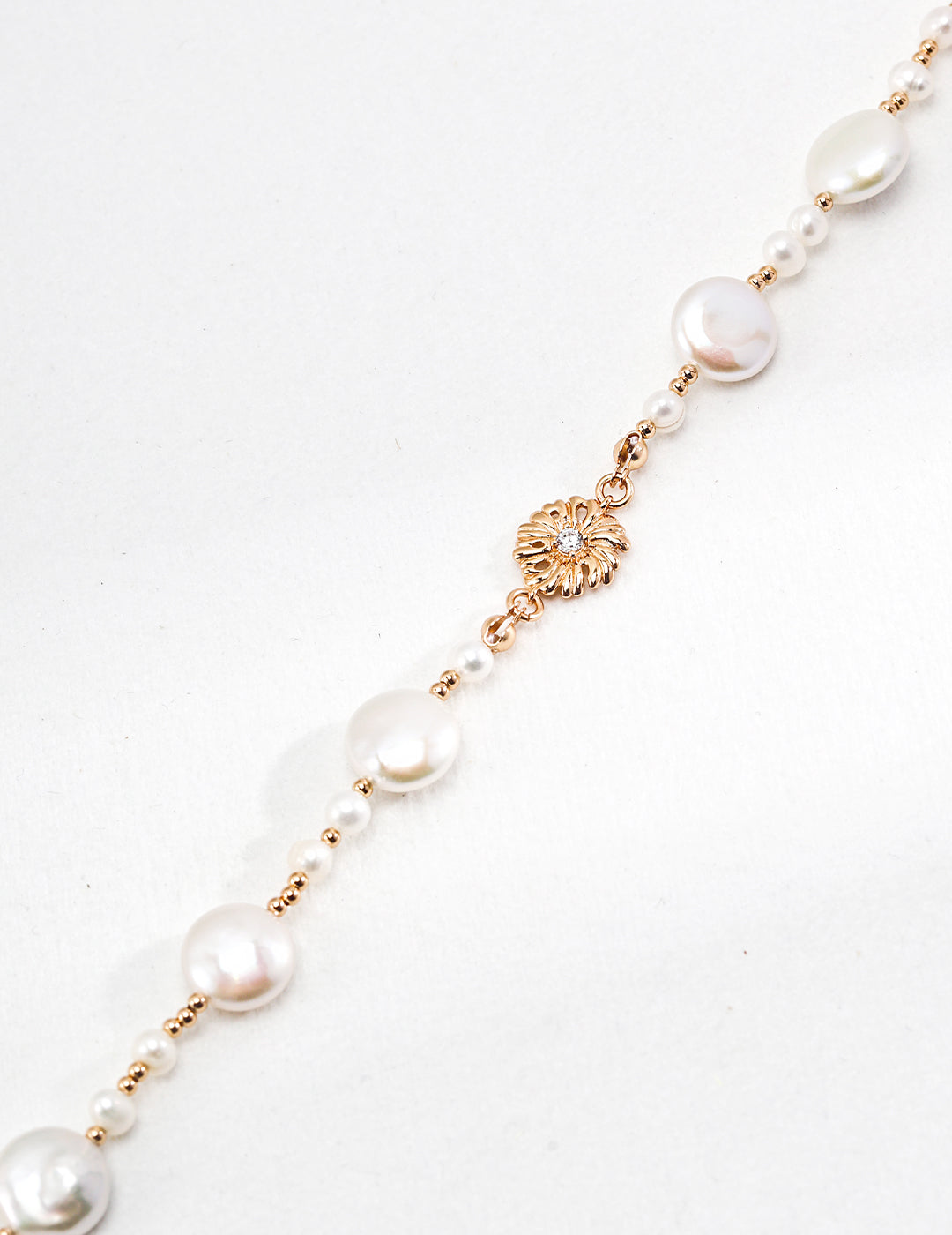 A gold necklace adorned with dainty beads and freshwater pearls.