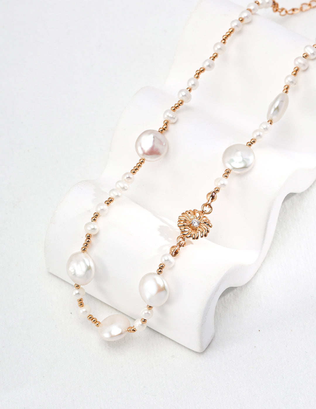 A stunning gold necklace with freshwater pearls and dainty beads, featuring a white pearl pendant and a gold clasp.