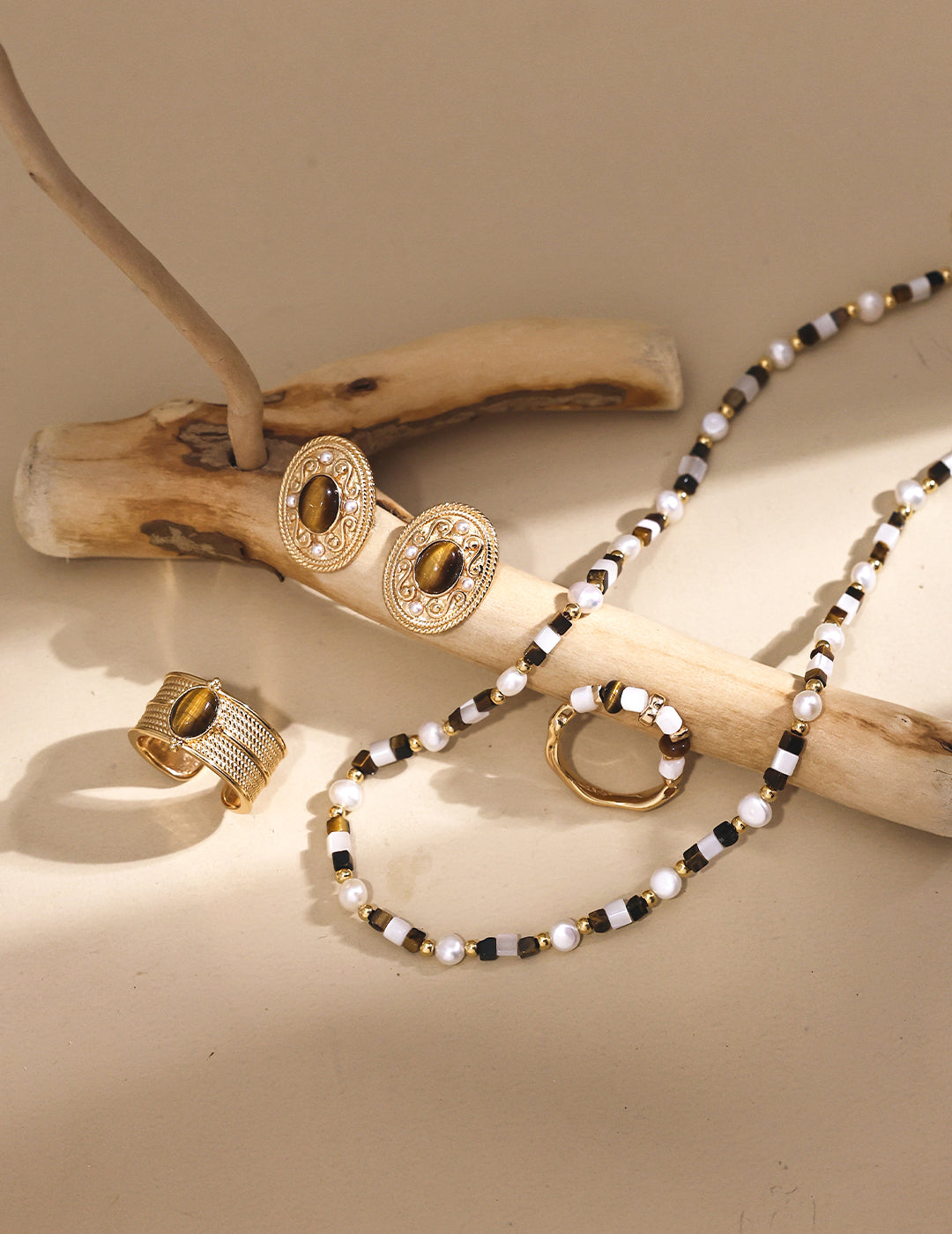 Elegant tiger's eye necklace, earrings, and bracelet artfully arranged on a wooden branch for a natural touch.