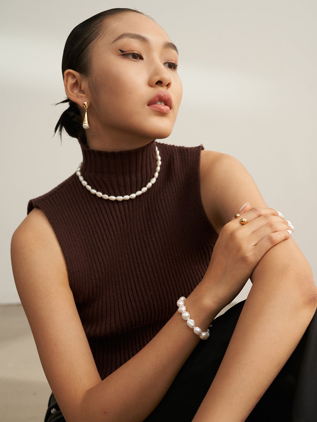 A stylish woman in a turtle neck top and pearl necklace exudes elegance and sophistication.