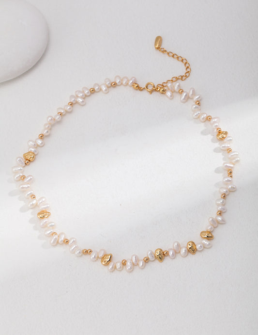 Elegant gold and white pearl necklace on white background.