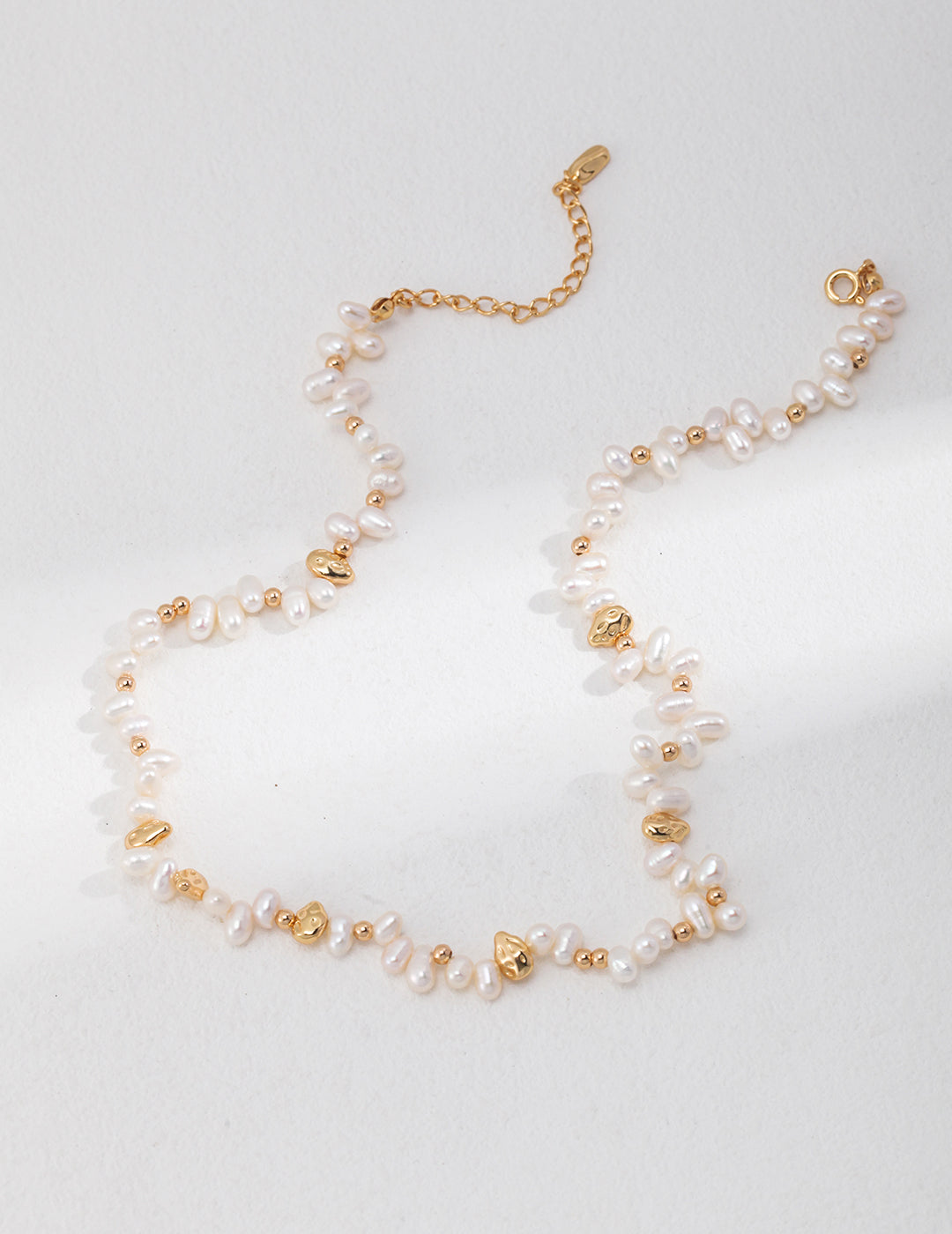 Stunning freshwater pearls necklace in gold and white on white base.