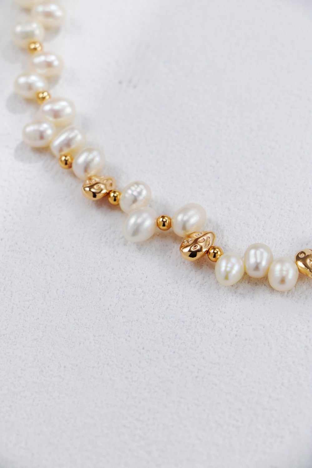 Macro close-up photograph focusing on the intricate details of the Natasha necklace, showcasing the natural, irregular shapes of the white pearls alongside molten-textured gold nuggets.