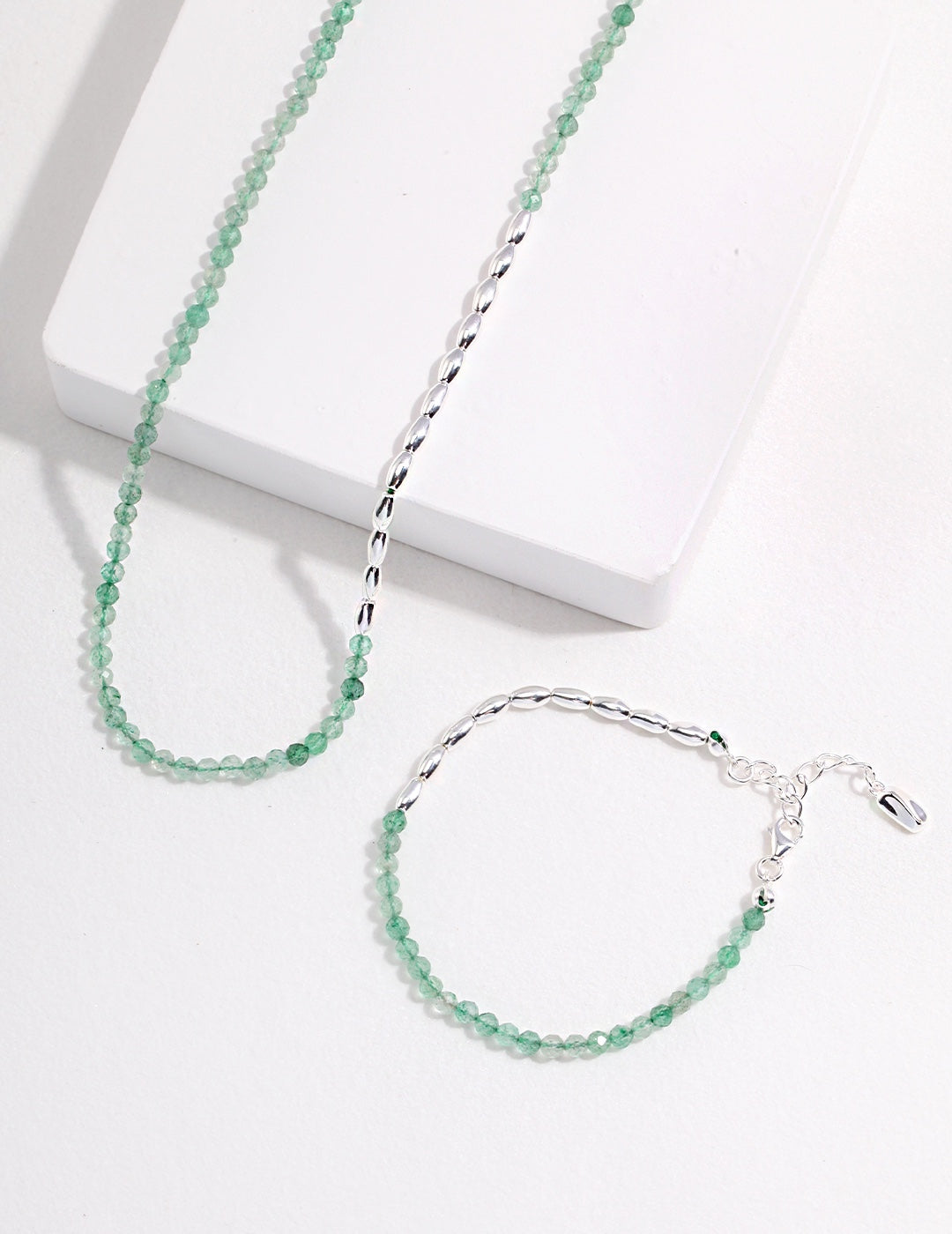 A stunning silver Green Strawberry Quartz necklace and bracelet set on a clean white surface.