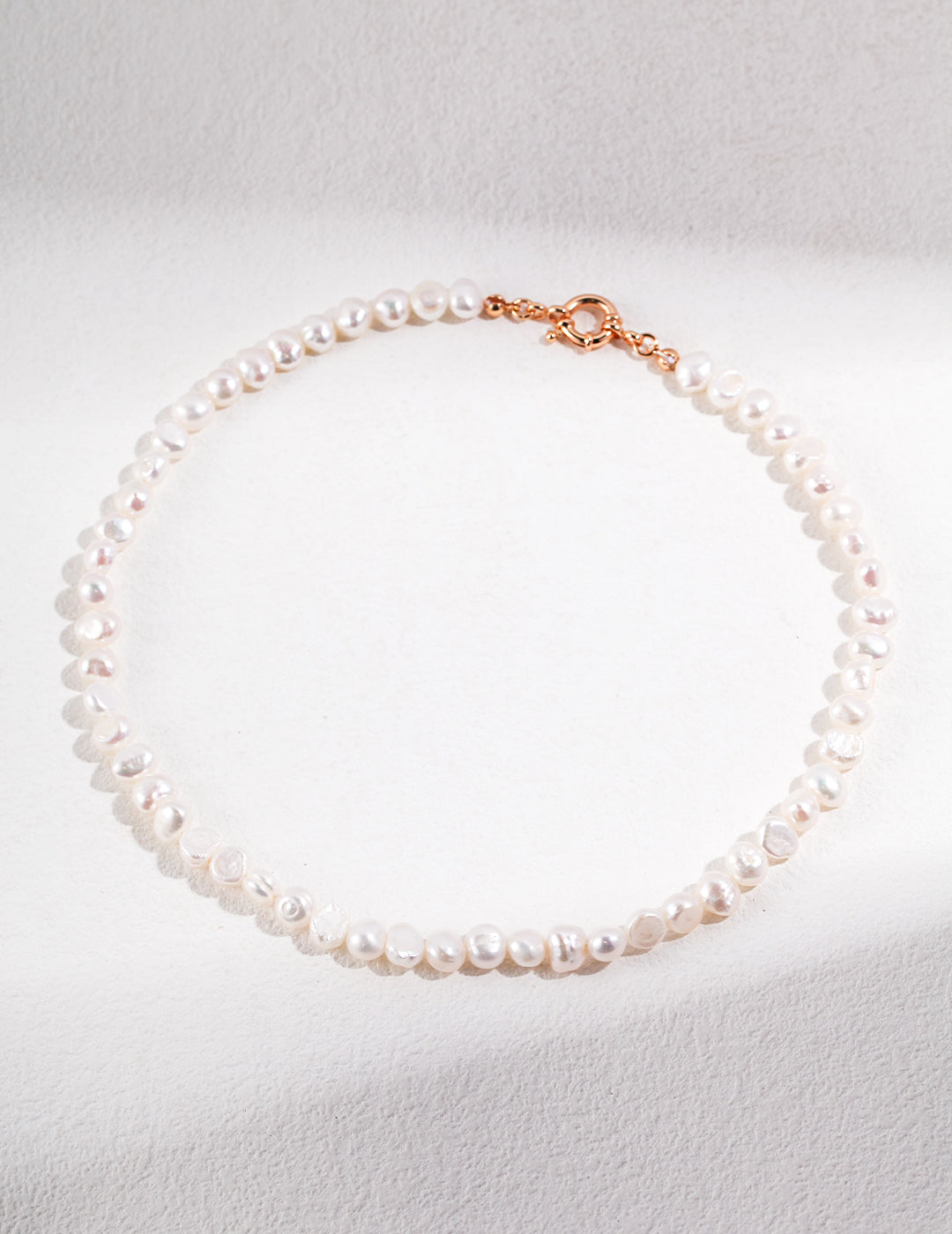 An elegant necklace showcasing baroque pearls, each distinct in shape, finished with a gold clasp. A refined accessory that radiates confidence and timeless style.