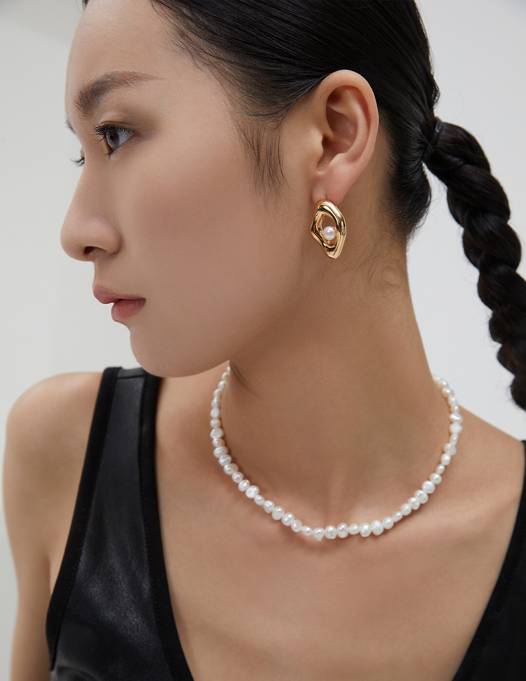 A striking look featuring baroque pearl jewelry—a refined necklace and bold gold earrings—exuding effortless elegance and confidence.