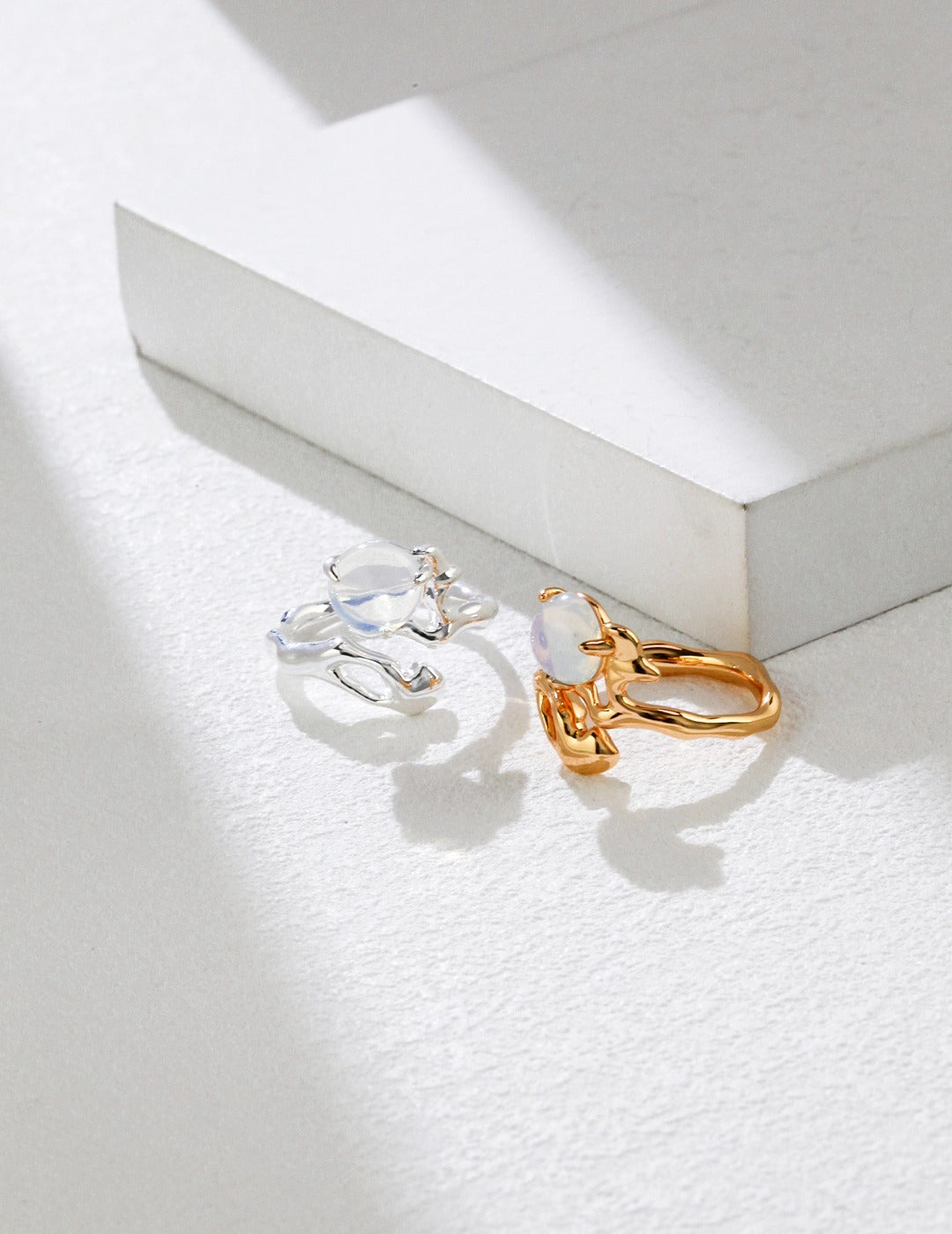 Elegant silver and gold opal rings with white stones on white.