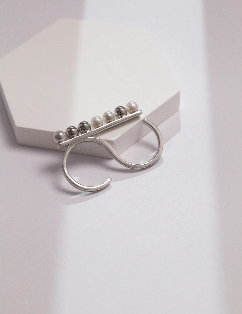 A silver minimalist two-finger ring adorned with shell pearls and beads, showcasing elegant shell pearls.