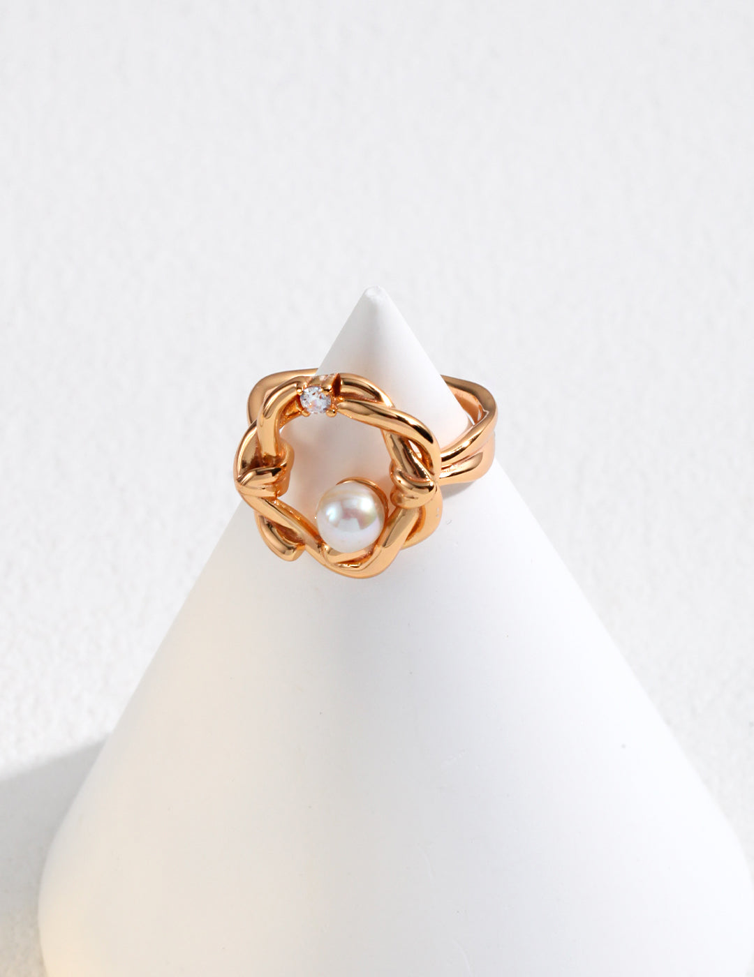 A stunning gold ring featuring a knot, adorned with a floral design, freshwater pearls, and cubic zirconia.