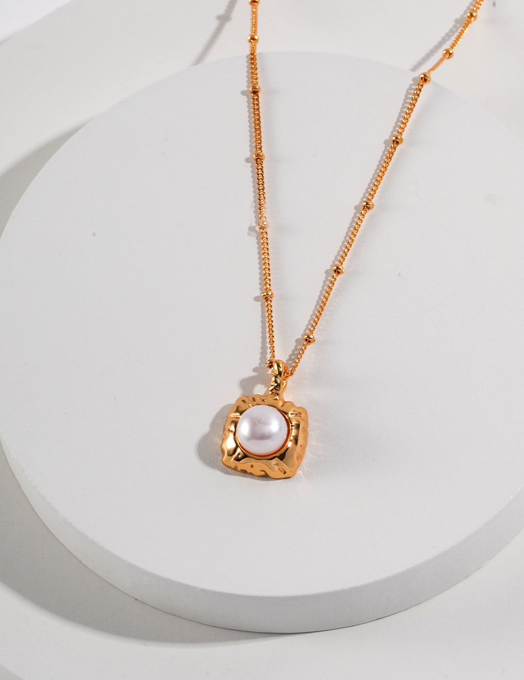 A stunning gold plated necklace featuring a square freshwater pearl pendant at its center.