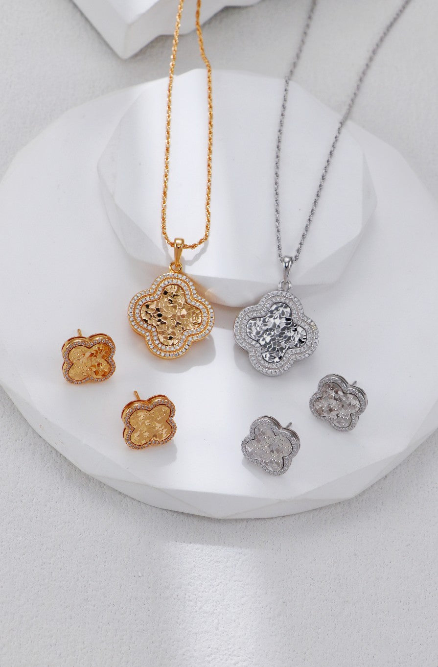 Sets of matching earrings and necklaces showcasing clover motifs, crafted in silver and gold with floral accents.