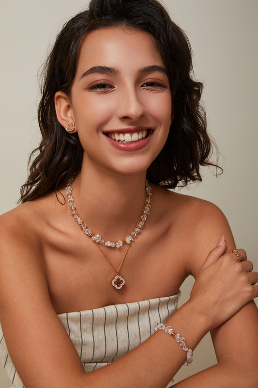Happy woman modeling a clover necklace and bracelet, radiating joy and style.