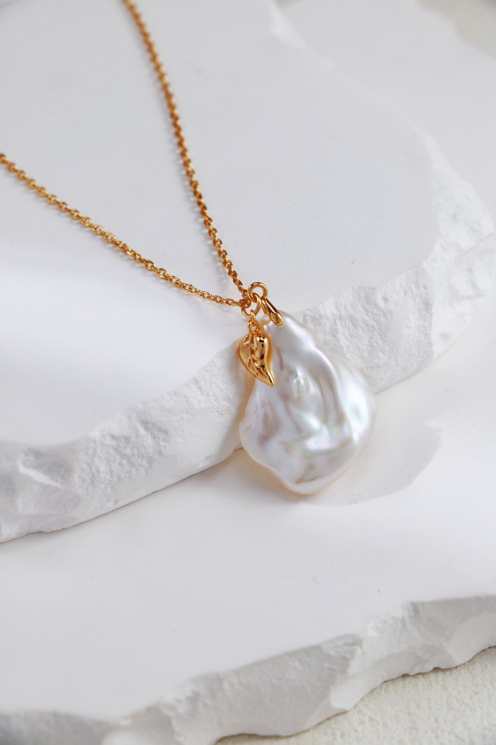 A beautiful pearl petal necklace showcased on a sleek white marble surface, highlighting its elegance and simplicity.