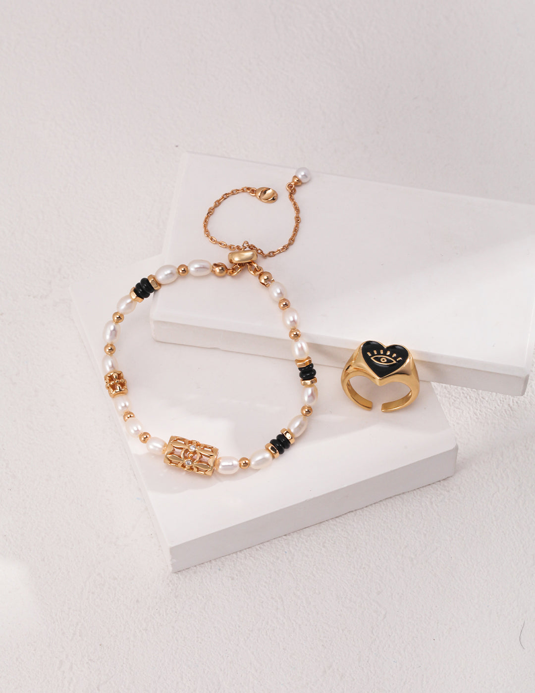 Elegant gold bracelet and ring set adorned with black beads, freshwater pearls, and dazzling cubic zirconia for a sophisticated touc