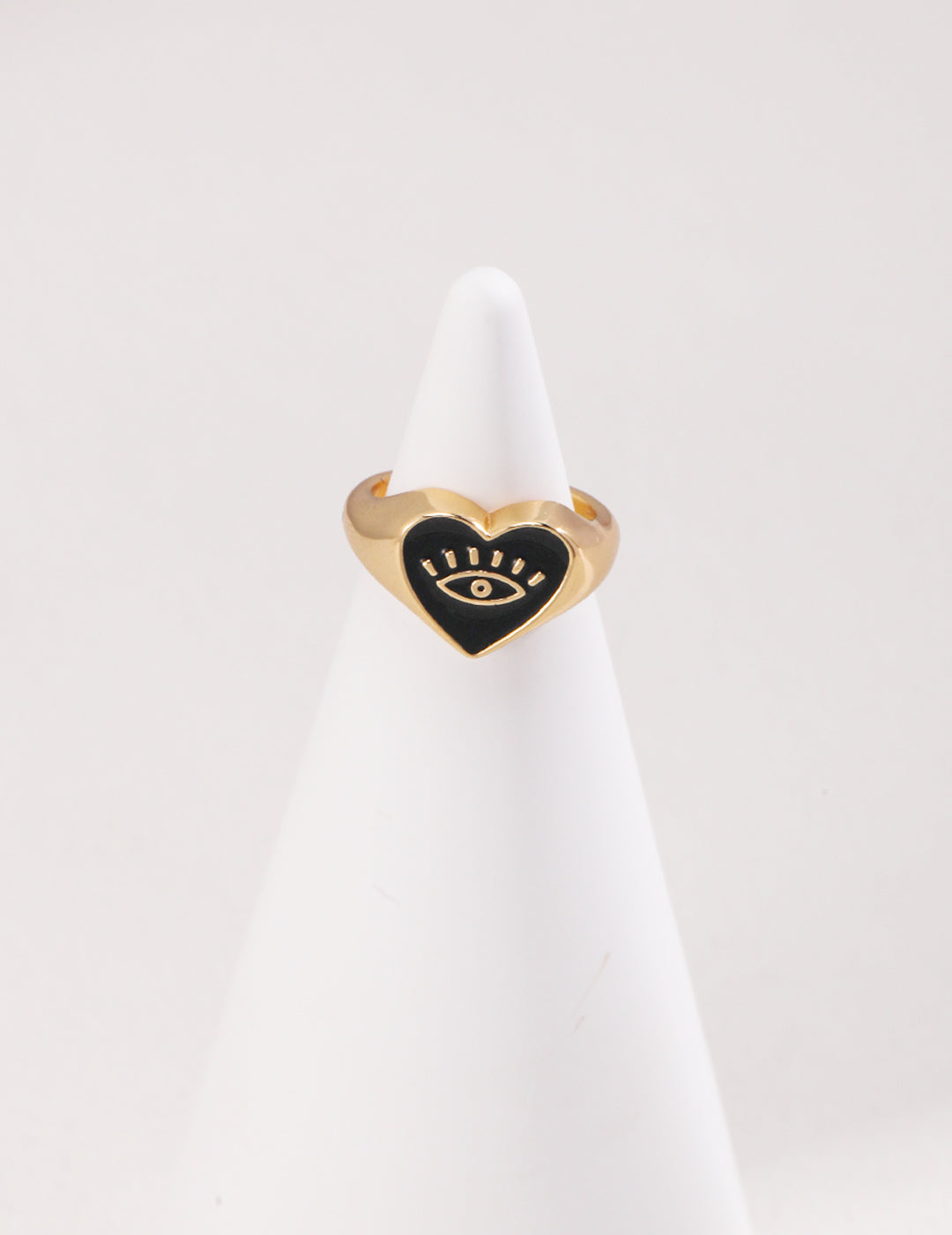 Heart-shaped gold ring with black enamel evil eye design.