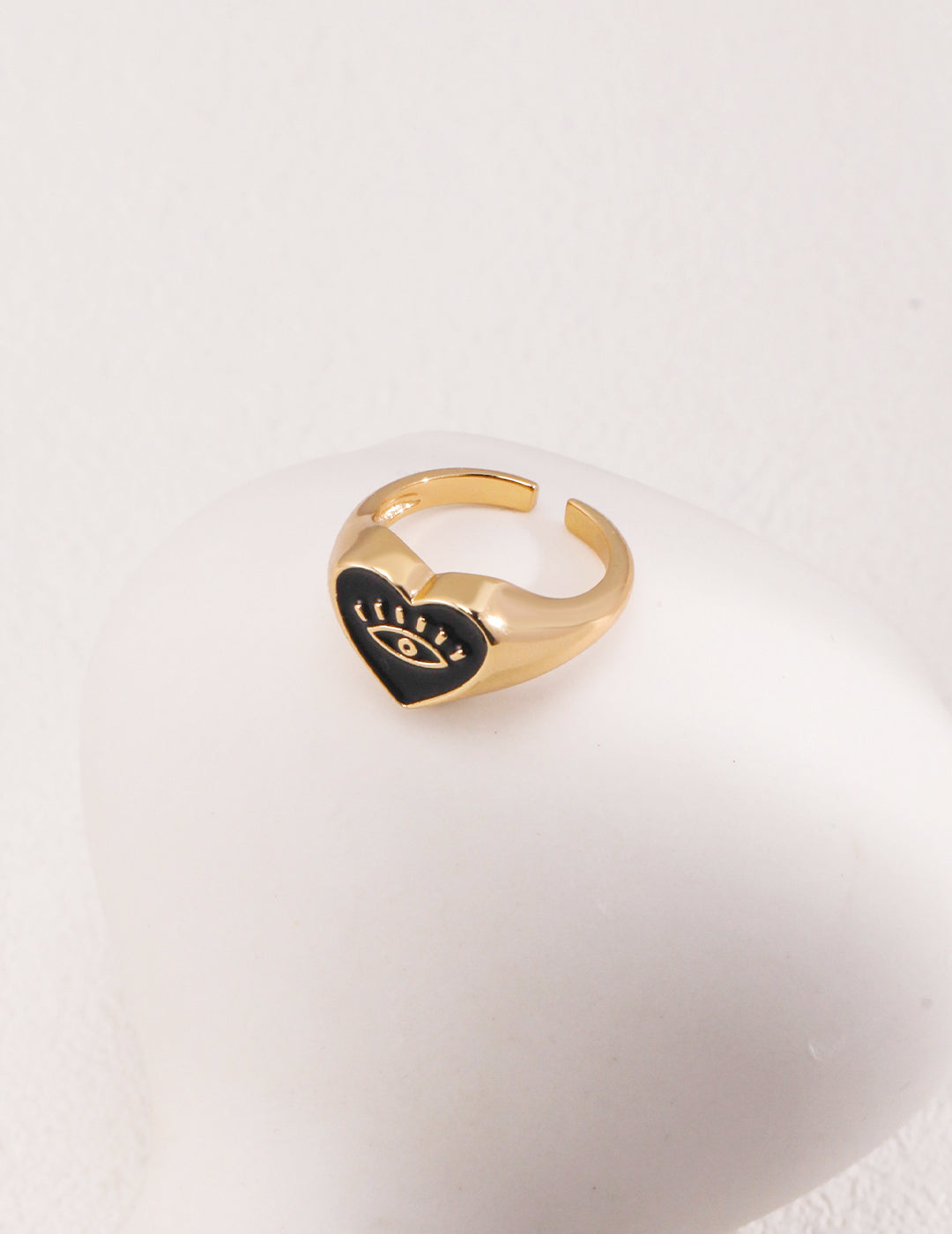 Black heart on gold ring, featuring evil eye design.