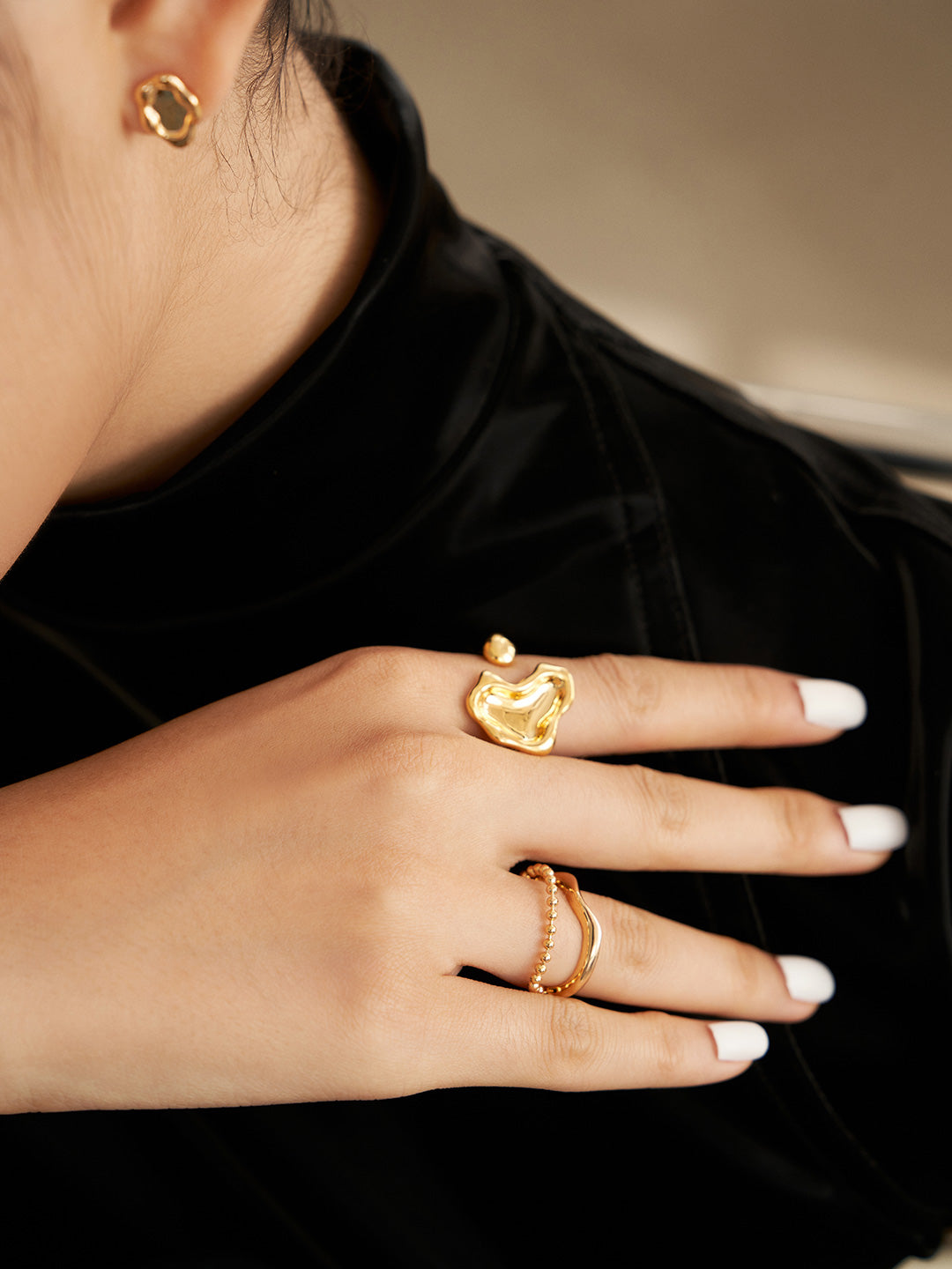 Stylish woman with gold ring and jewelry in black top.