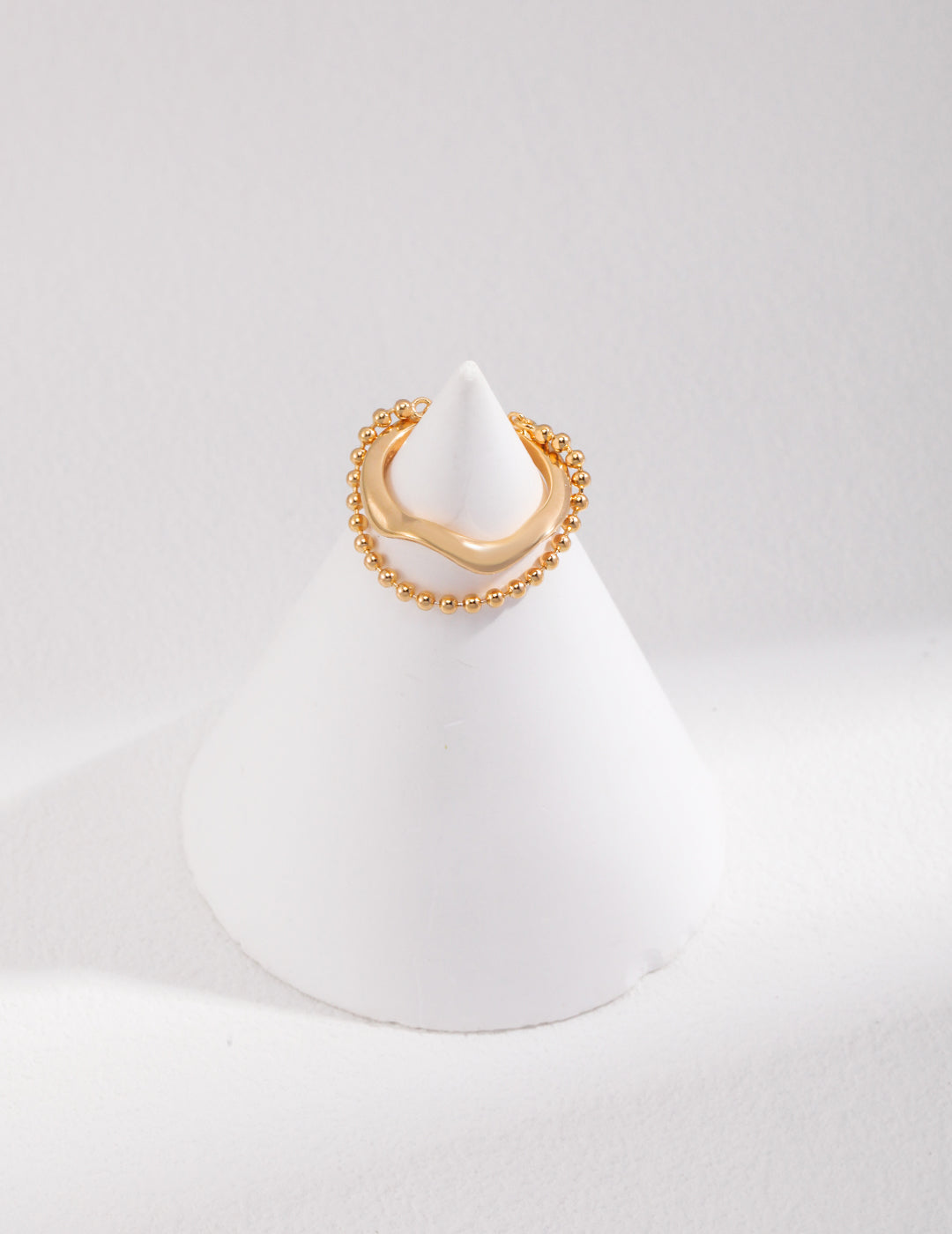 Gold duo layered ring on white cone