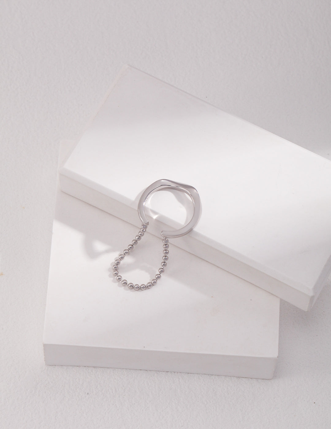 A duo layered silver ring and a white box on a white surface.