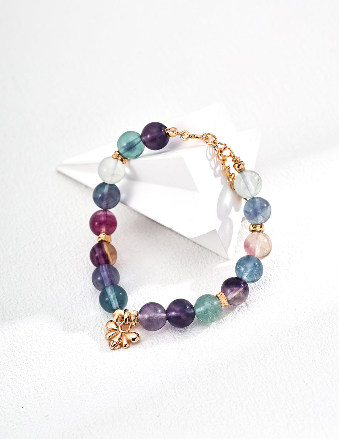A colorful fluorite bracelet with a gold charm, displaying a beautiful array of multi-colored stones.
