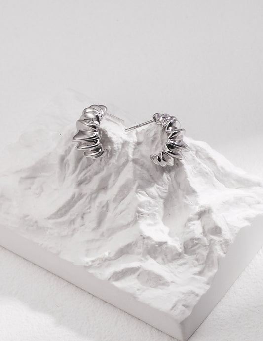 A stunning pair of silver earrings resting atop a majestic mountain peak prop