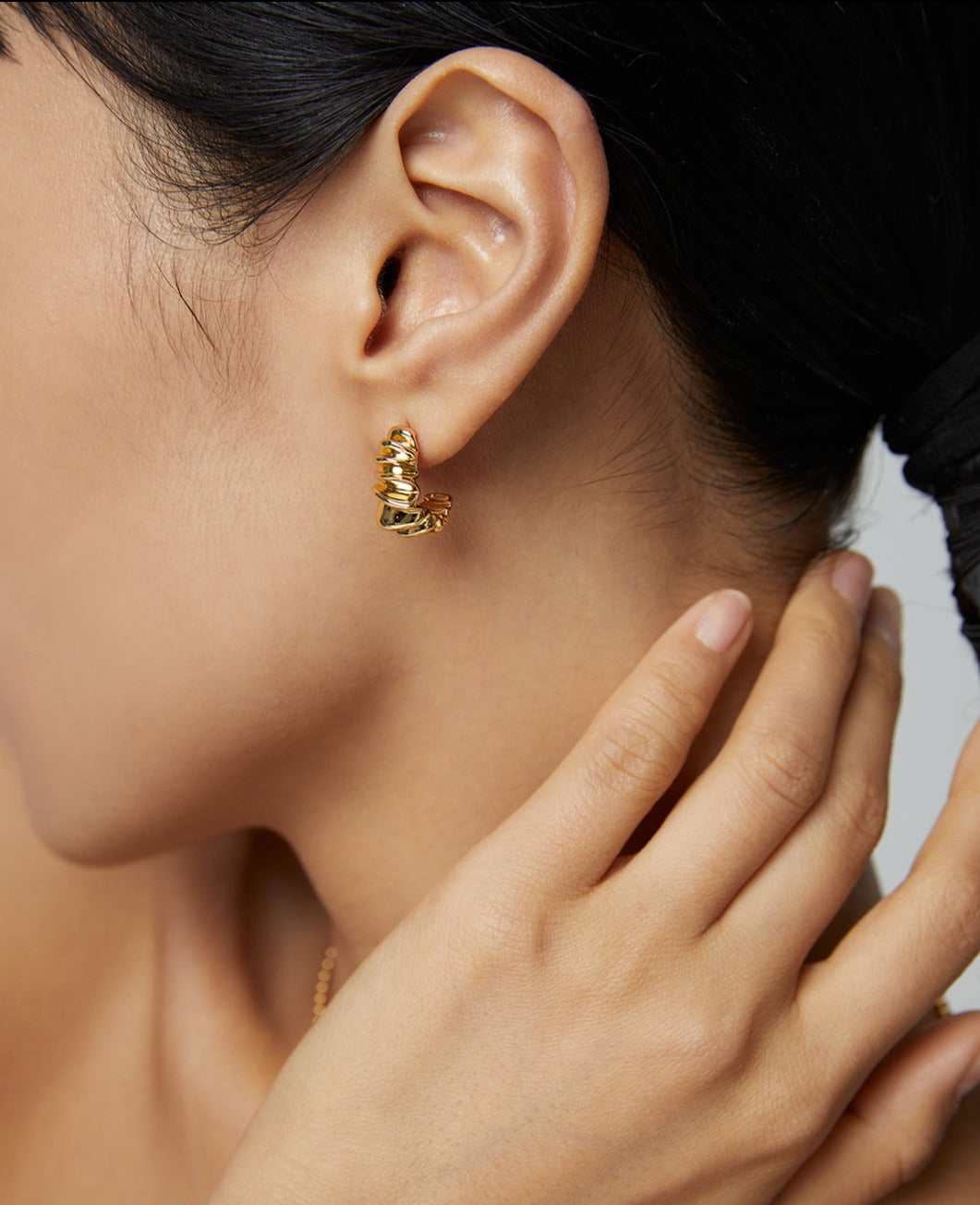 A woman wearing a gold earring with a zigzag design, adding a touch of elegance and intrigue.