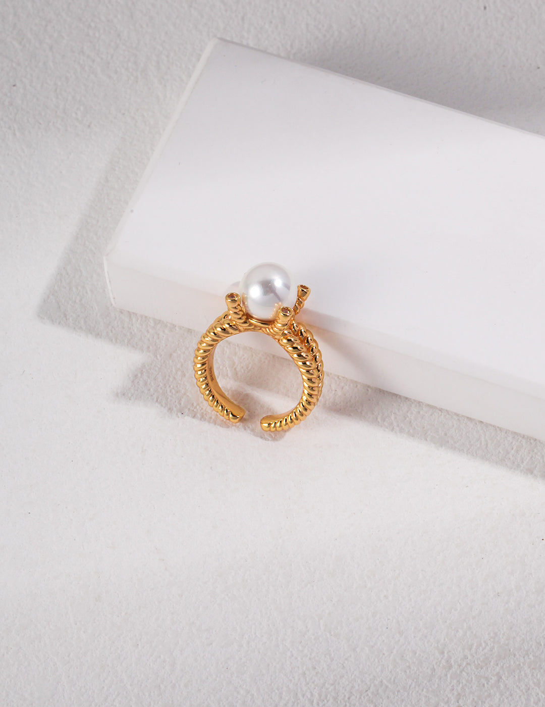 Gold braided band ring with a lustrous shell pearl centerpiece.