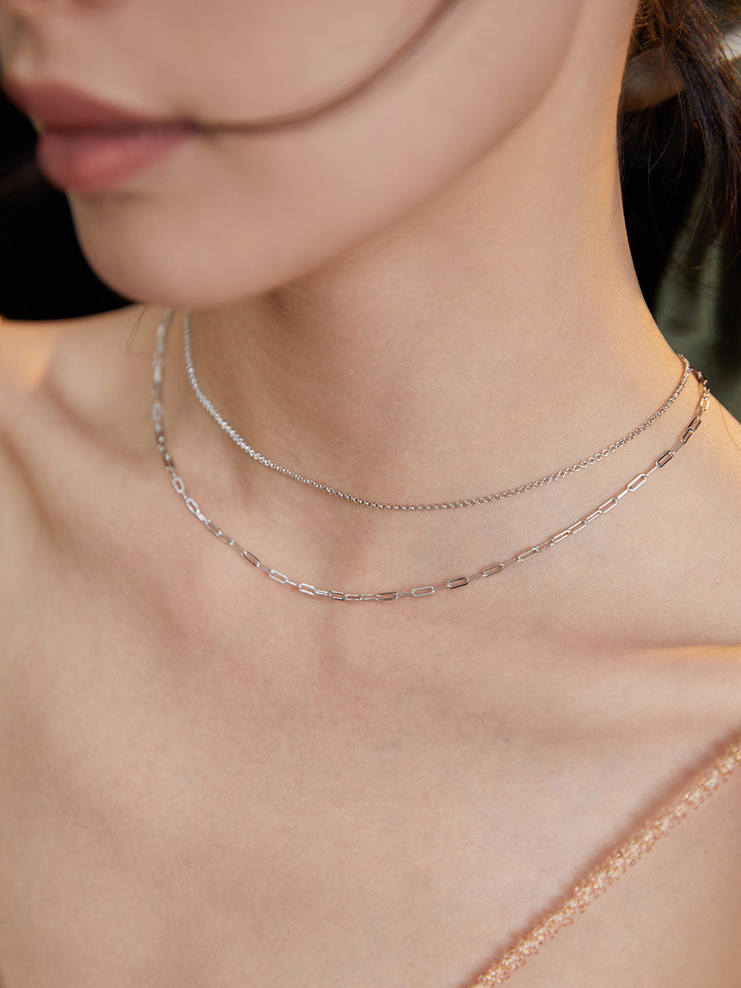 Silver necklace and chain on woman.