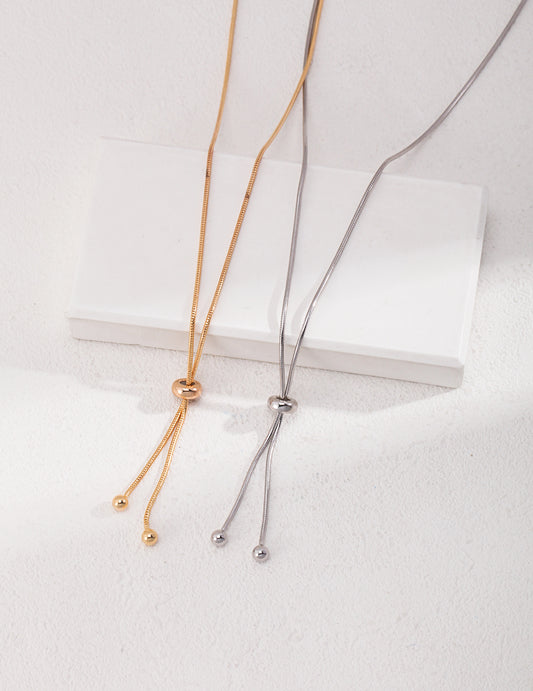 Two minimalist silver and gold necklaces with knots on each end.