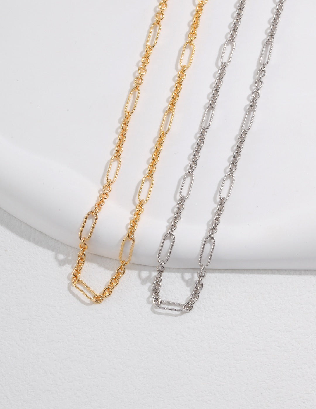 Two elegant necklaces, one silver and one gold, featuring delicate chains with small links.