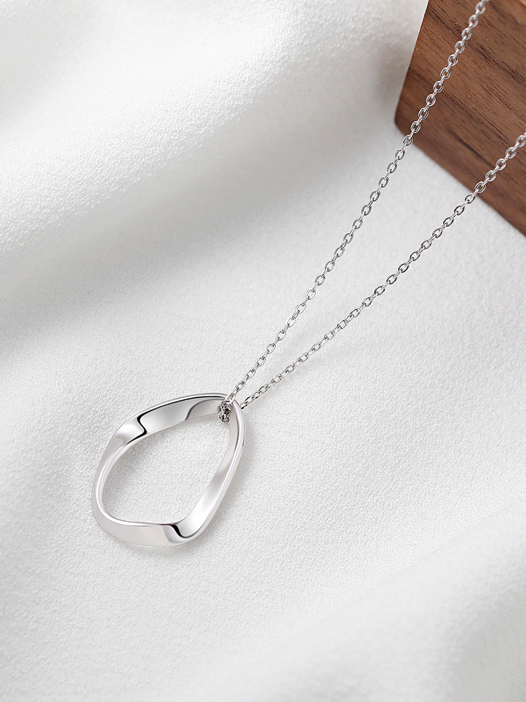 Circular silver pendant on chain necklace.