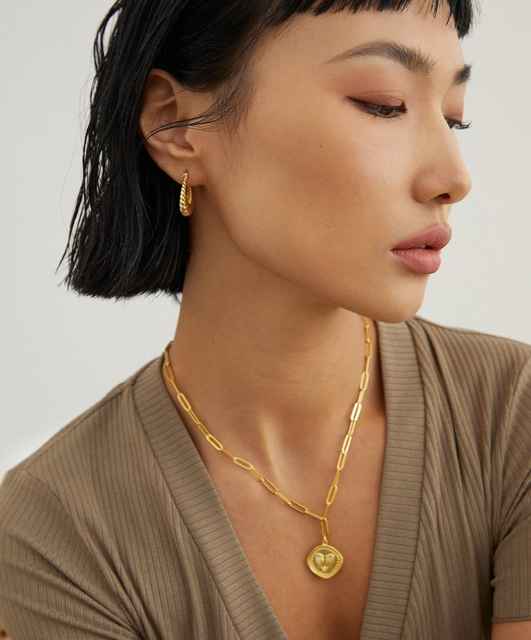 A woman wearing elegant gold jewelry, including a necklace and earrings, adding a touch of sophistication to her attire.