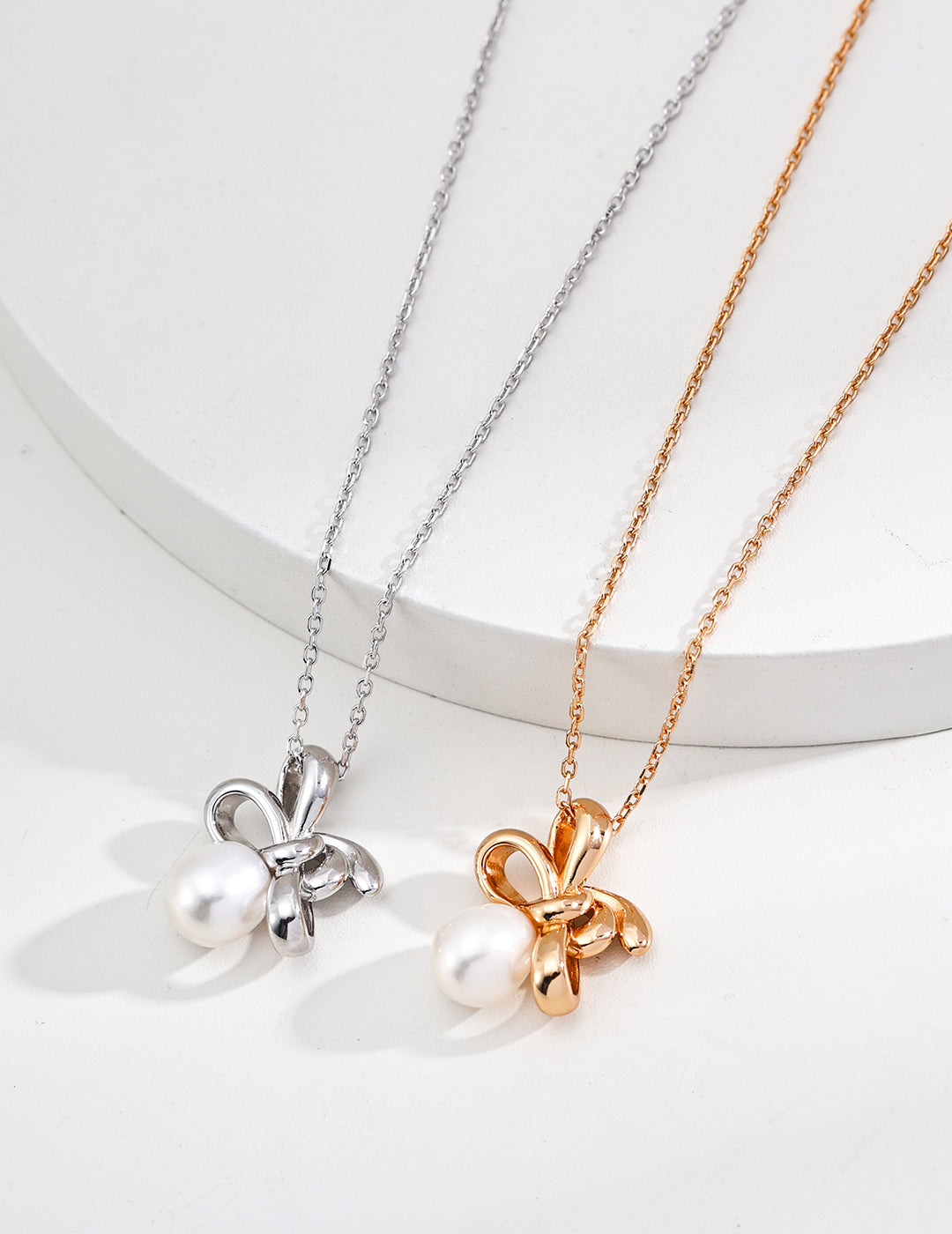 Two necklaces with pearls in playful twist knot designs, one silver and one gold, perfect for any occasion.