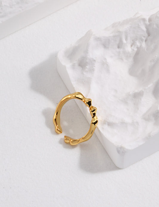 A simple gold ring with a thin band resting on a rock.