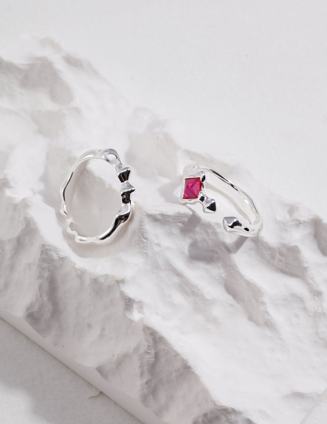 Assortment of thin silver rings displayed on a rock.