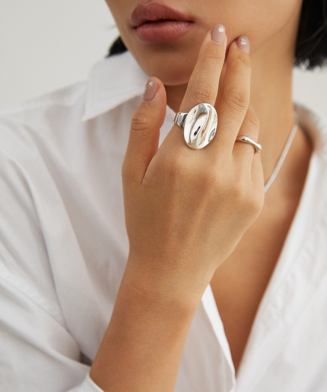 Woman wearing white shirt, wearing a silver coffee bean ring.