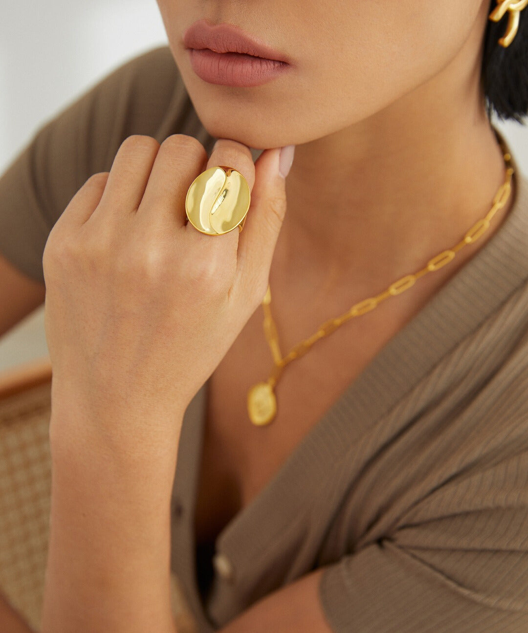 A woman flaunting a gold coffee bean inspired ring and necklace, exuding style and sophistication.