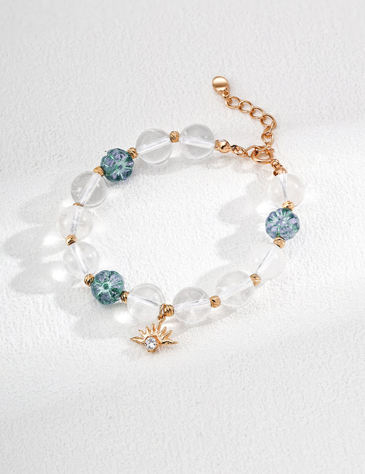 Elegant bracelet made of clear glass beads and gold-plated charms, including round and flower-shaped designs.