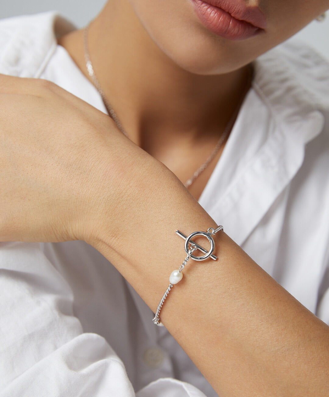 A woman wearing a bracelet with freshwater pearls on a silver chain.