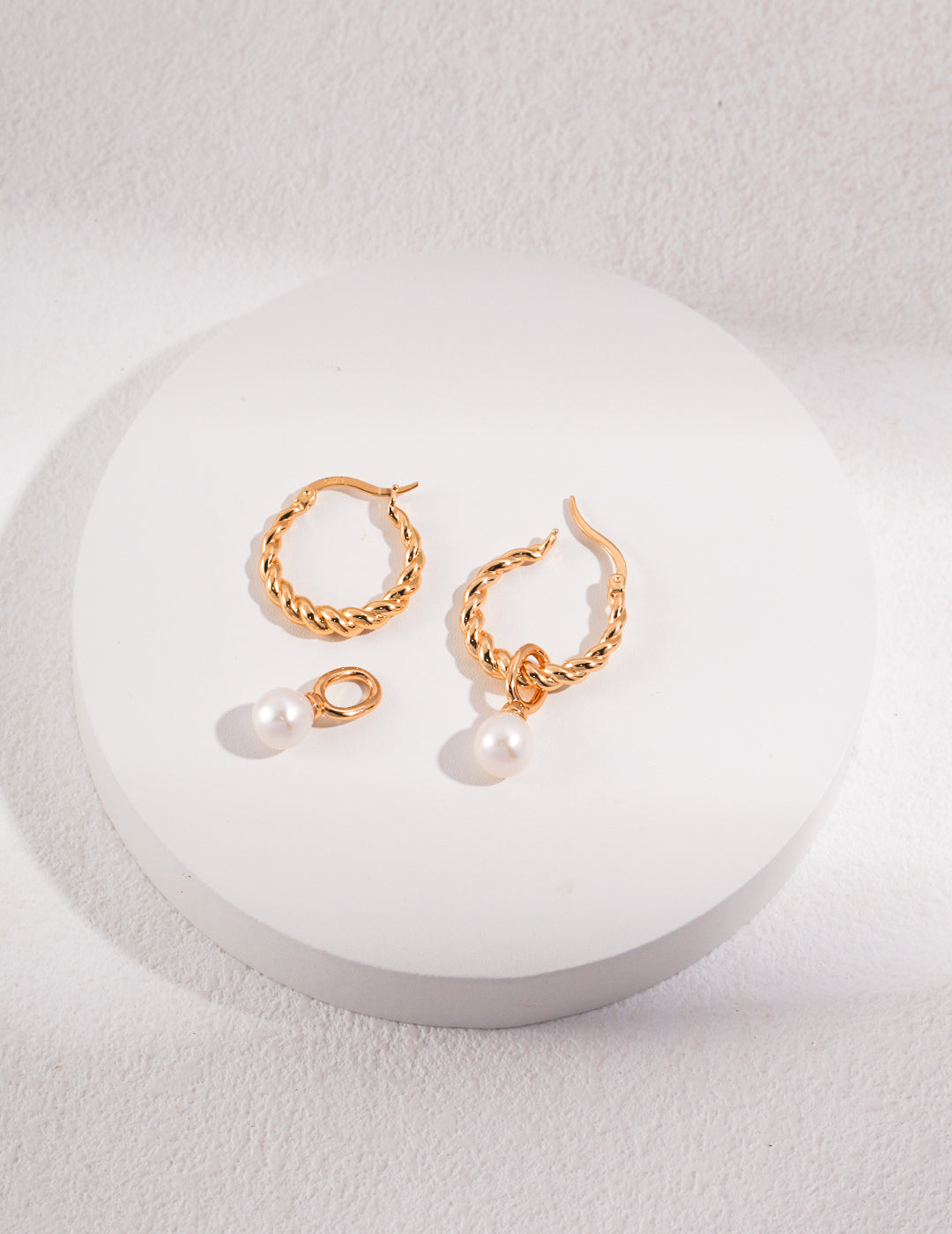 Stylish gold hoop earrings featuring freshwater pearls on white surface.