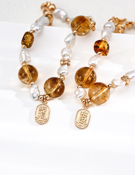 Two elegant gold-plated bracelets with a crystal charm, embellished with tiger's eye and pearl details.