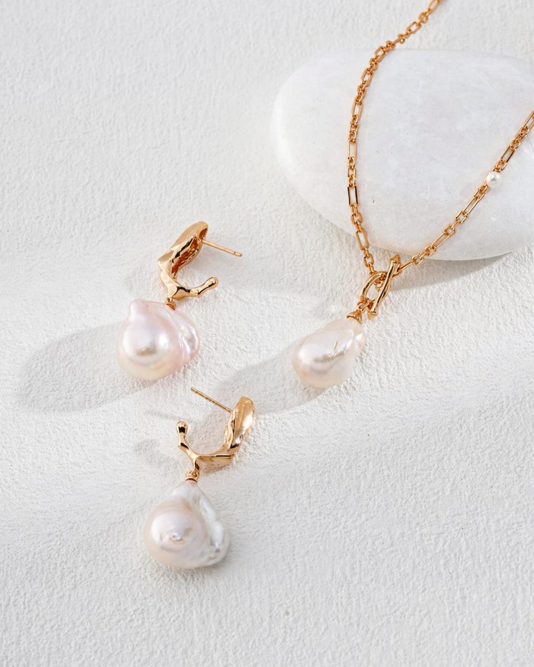 A styled product photograph of The Baroque Pearl Duo set, featuring the Anastasia toggle necklace and Genevieve baroque pearl drop earrings arranged together on a clean white surface.