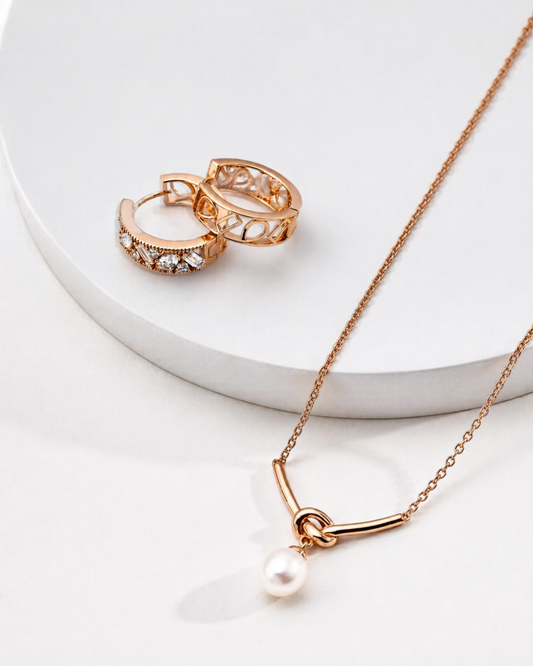 A styled product photograph of The Everyday Duo set, featuring the Love Me Knot pearl necklace and Edith cubic zirconia hoop earrings arranged together on a neutral surface.