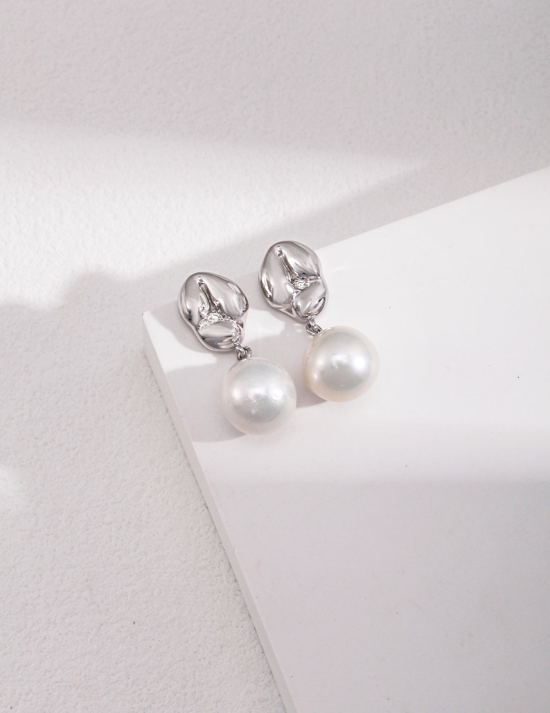 Elegant silver plated pearl drop earrings on white background.