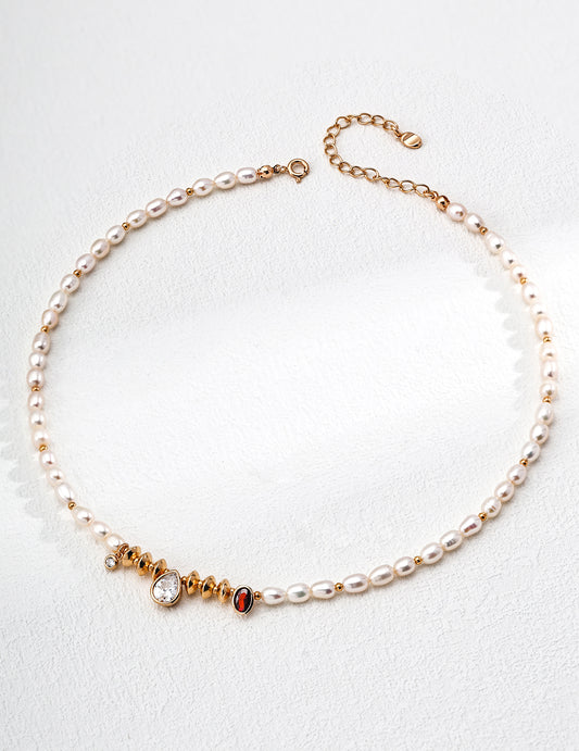 Regal gold and white pearl necklace showcasing a vibrant red and white stone, complemented by cubic zirconia and freshwater pearls.