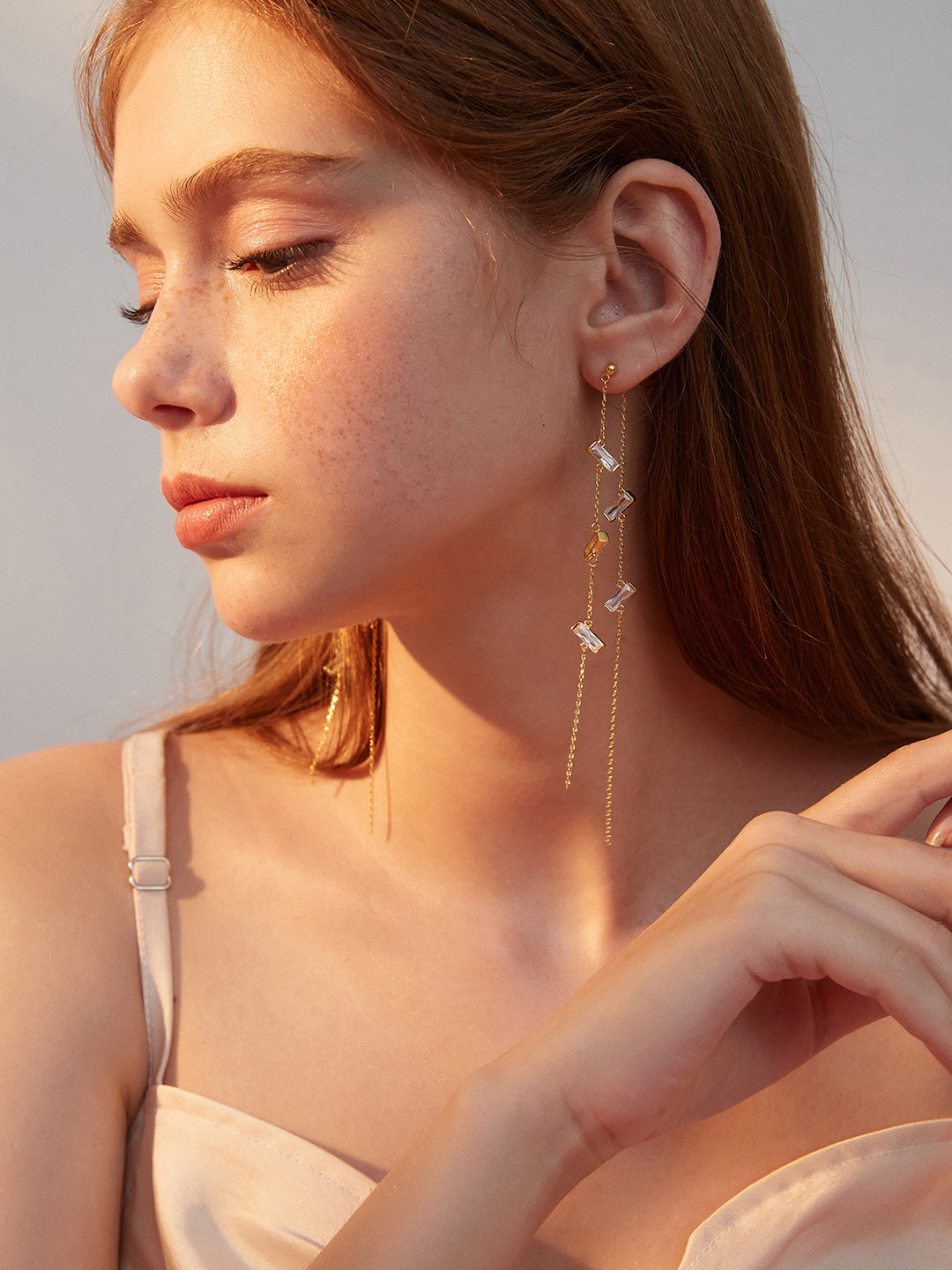 Woman showcasing a gold chain cubic zirconia dangling earring.