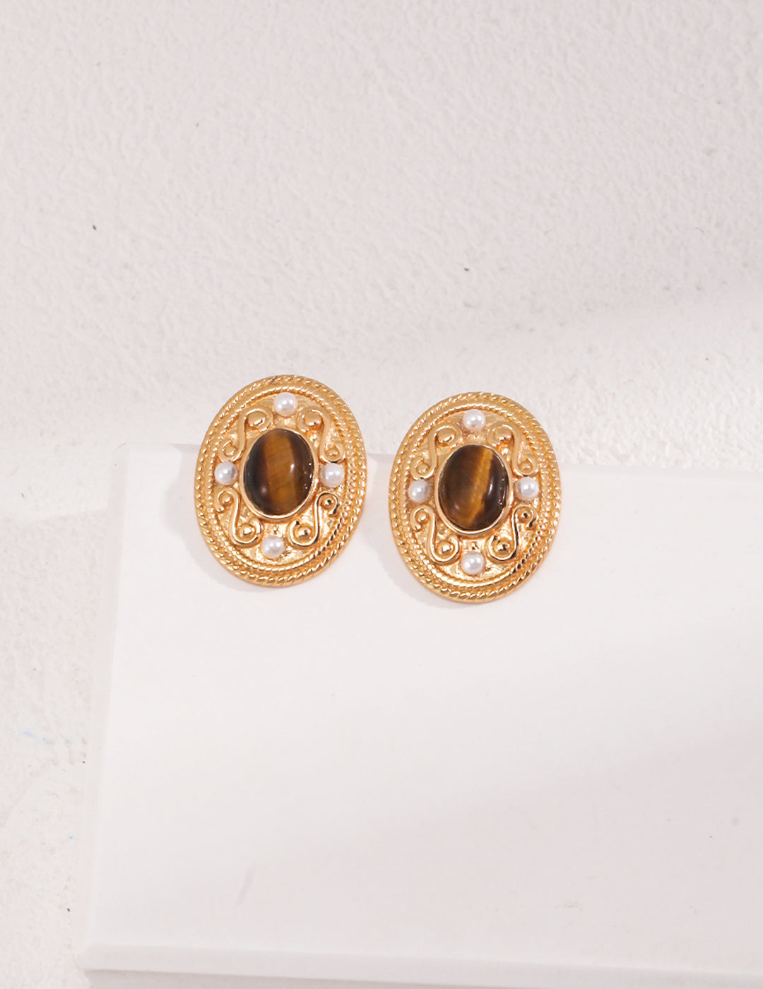 Elegant gold tone earrings adorned with circular pattern, pearls included.